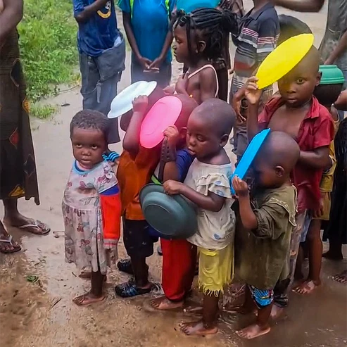 Niños en fila con platos vacíos